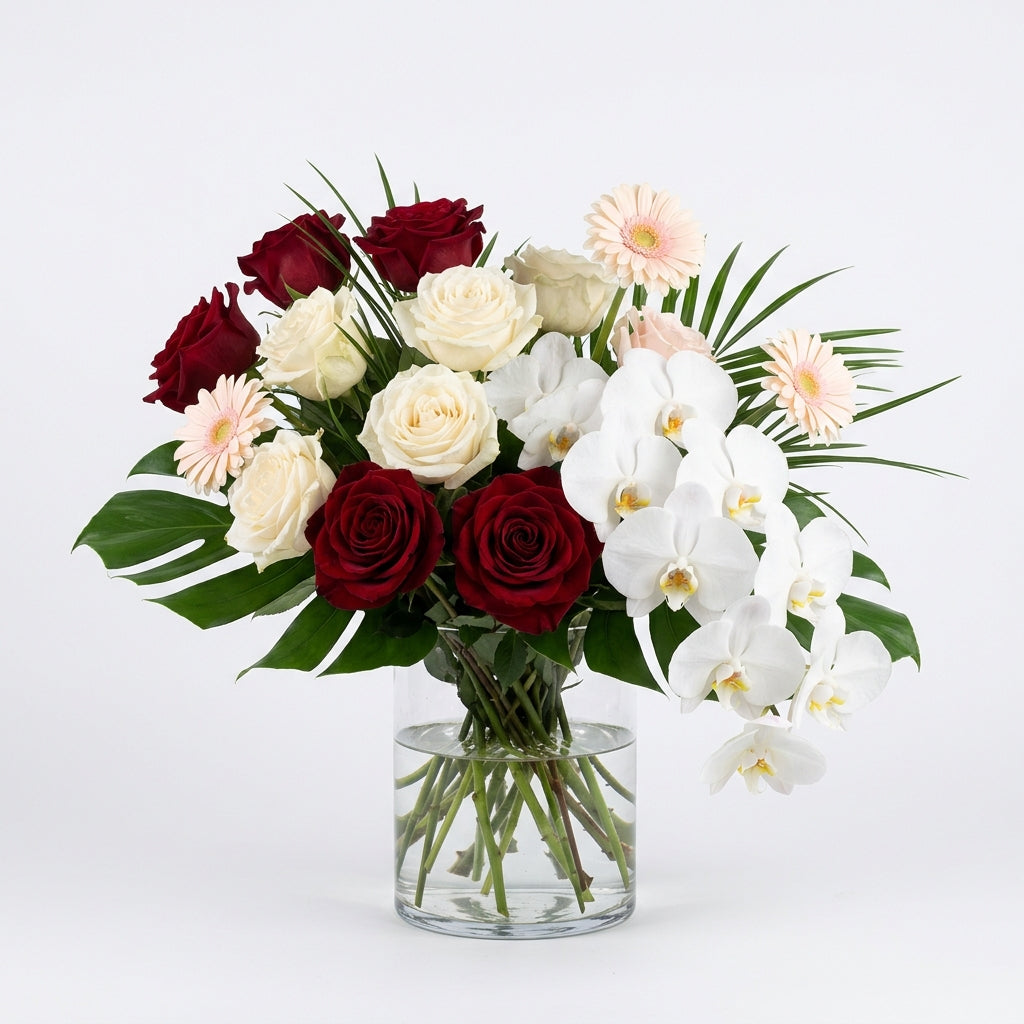 Feliz Cumple Luxe birthday arrangement with red and cream roses, cascading white orchids and pale pink gerbera daisies.