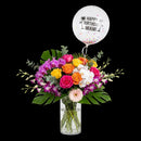 Fiesta & Blooms arrangement with colorful roses, purple and white orchids, tropical leaves and a Happy Birthday Miami balloon.