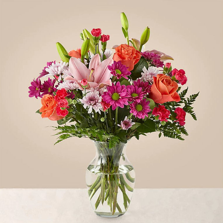 Flash of love Flowers Deluxe Bouquet And Vase, Blooms With Vibrant Color And a Sweet Sophistication To Make An Unforgettable Impression! Pink Lilies Dance Over The Distinctive Arrangement Of This Flower Bouquet, Which Is Surrounded By Orange Roses, Lavender Cushion Poms, Hot Pink Carnations, And Rich Greenery. Bouquets Flowers in Coral Gables, Miami, Delivery Flowers, Florist in Coral Gables.