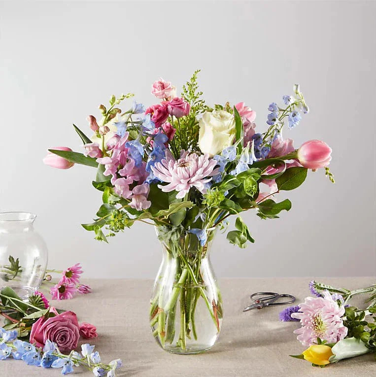 Colorful spring flower bouquet with roses, tulips, and chrysanthemums in a clear vase