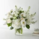 Elegant white roses, hydrangeas, and gerbera daisy flower arrangement in clear glass vase