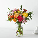 Bright mixed flower bouquet with roses and lilies in a glass vase for flower delivery